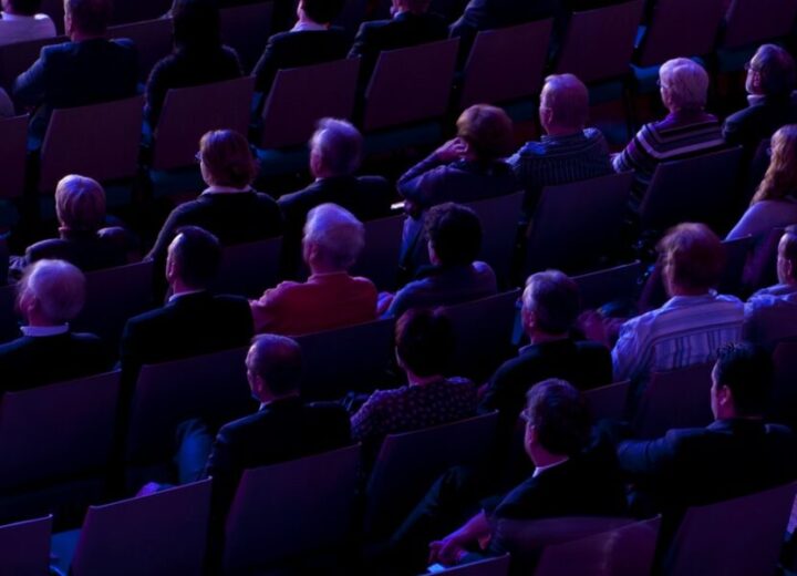 Audience Seated In Dimly Lit Venue.
