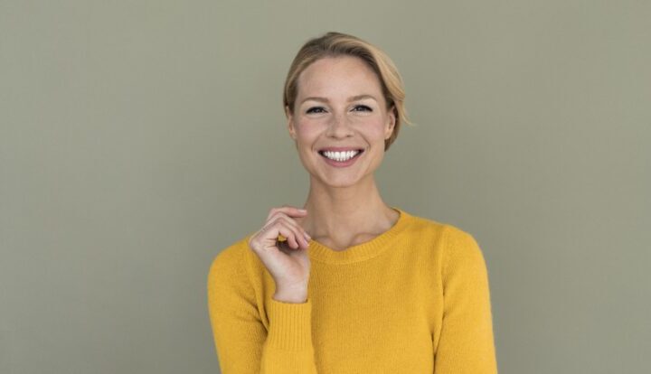 Woman In Yellow Sweater Against Green Wall.